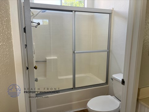 A white toilet is in a bathroom with a walk-in shower.